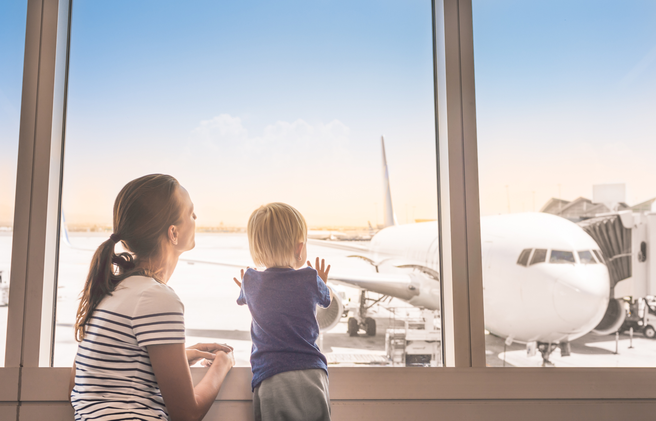 Mutter mit Kleinkind am Flughafen-Fenster