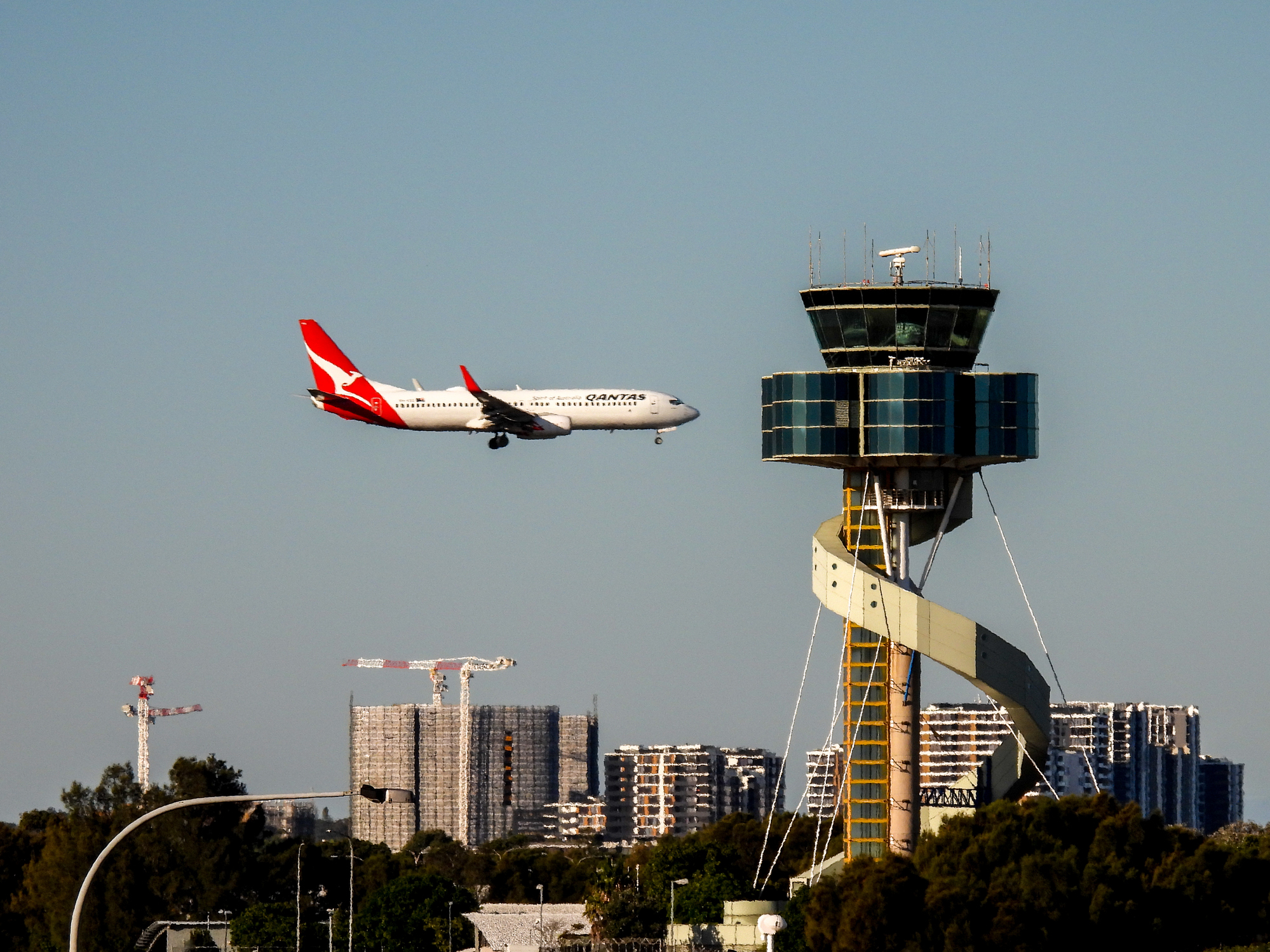 Eine Qantas-Maschine befindet sich im Landeanflug auf den Flughafen Sydney, weiter hinten steht der markante Flughafen-Tower. 