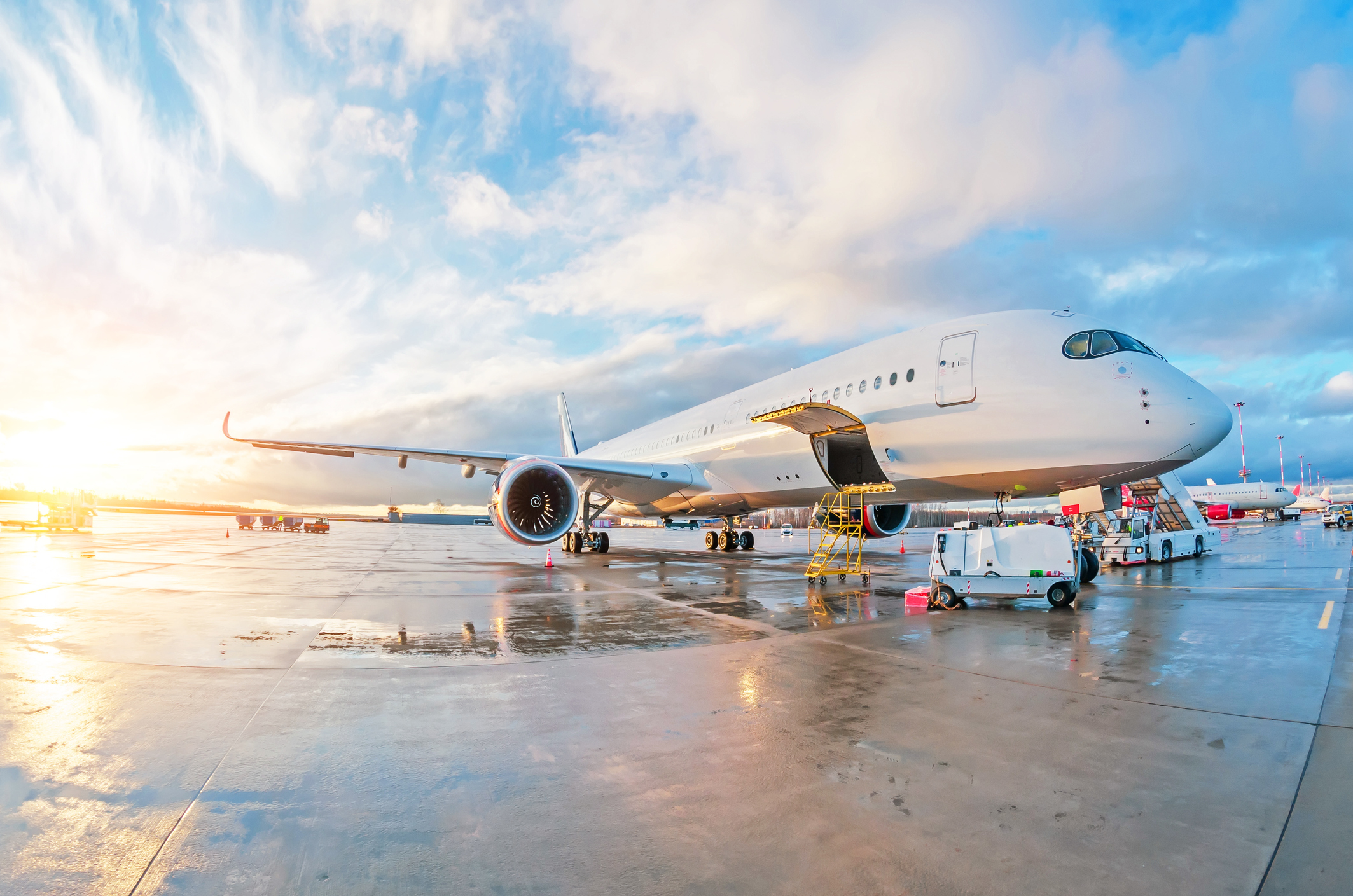 Onderhoudswerkzaamheden aan een geparkeerd passagiersvliegtuig op natte grond op de luchthaven bij zonsondergang
