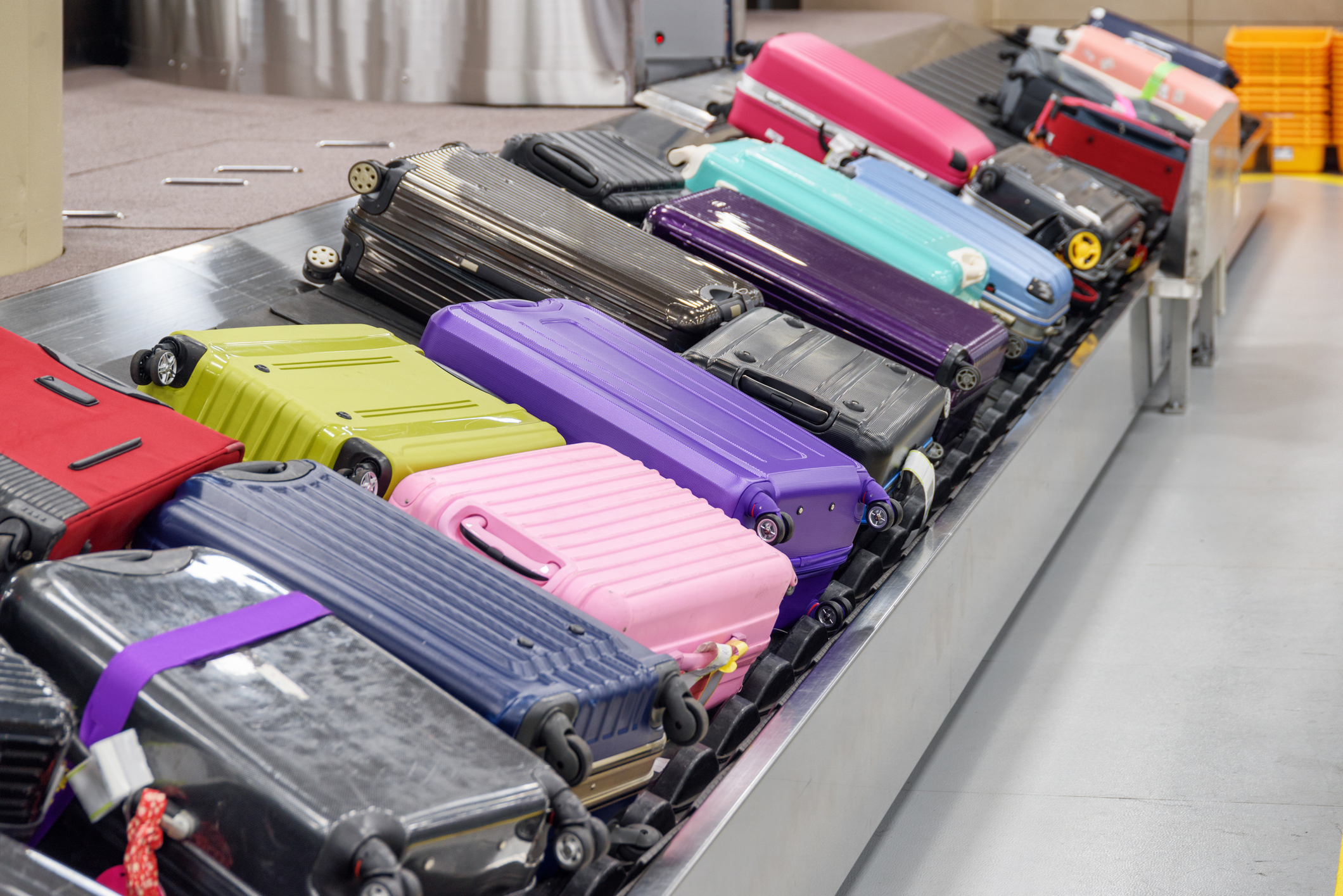 Koffer stapeln sich in großer Menge auf einem Gepäckband.