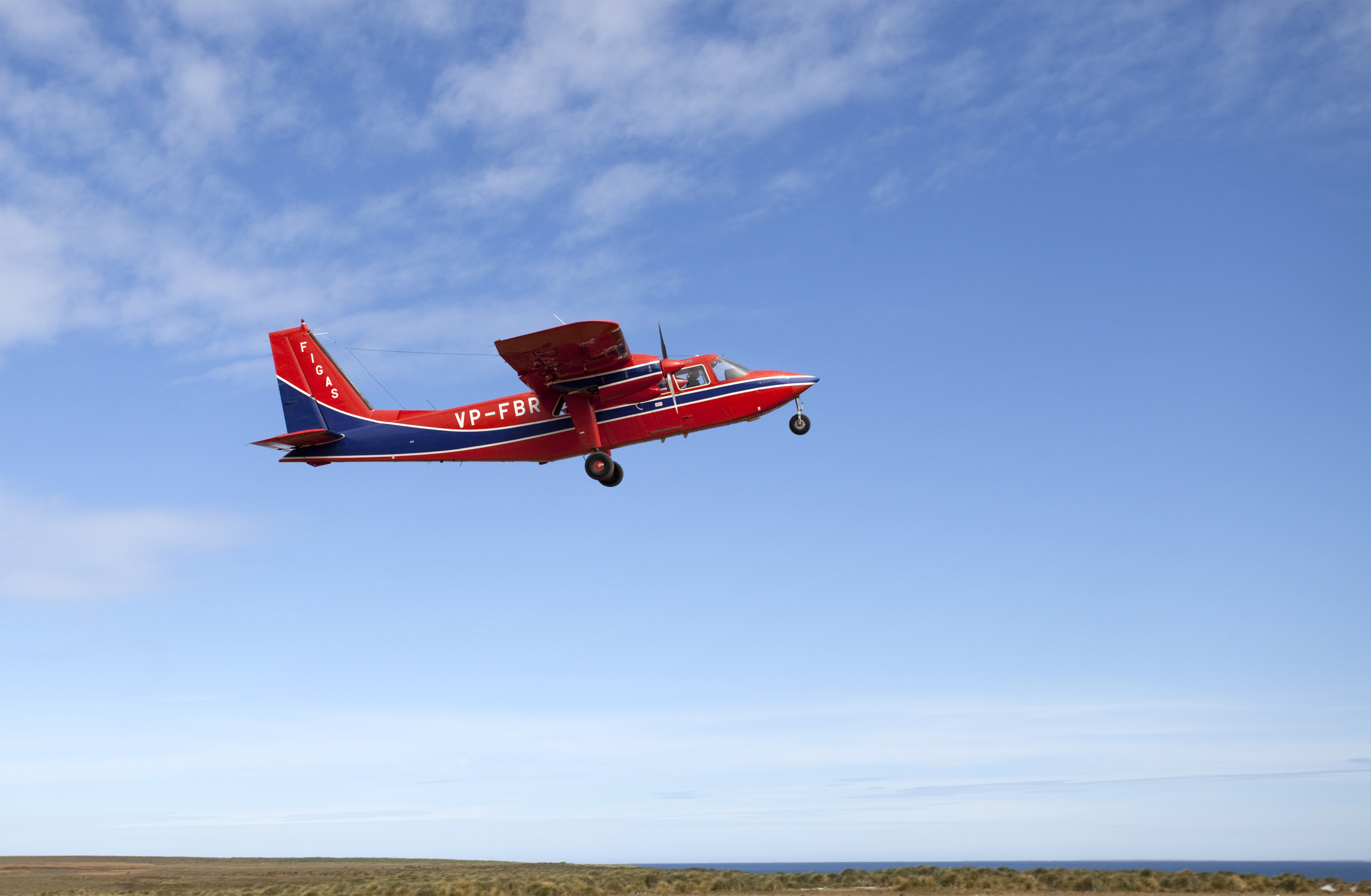 Ein rot-blaues Propellerflugzeug hebt bei gutem Wetter ab.