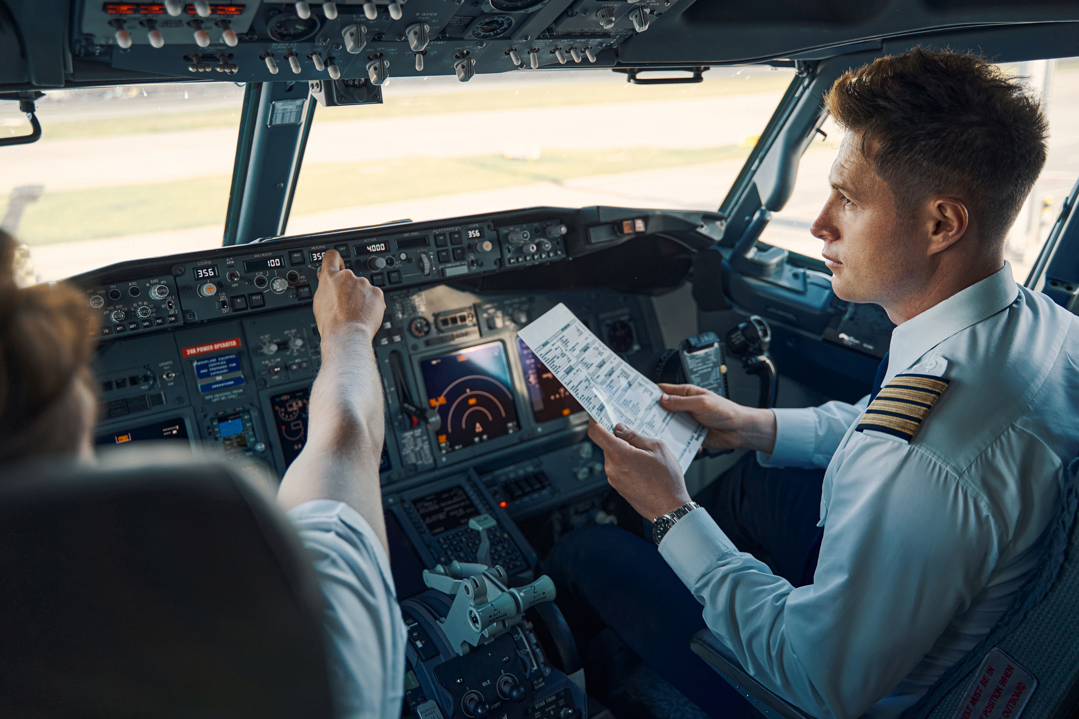 Co-piloot met een checklist voor de vlucht, zittend naast de chief pilot in de cockpit