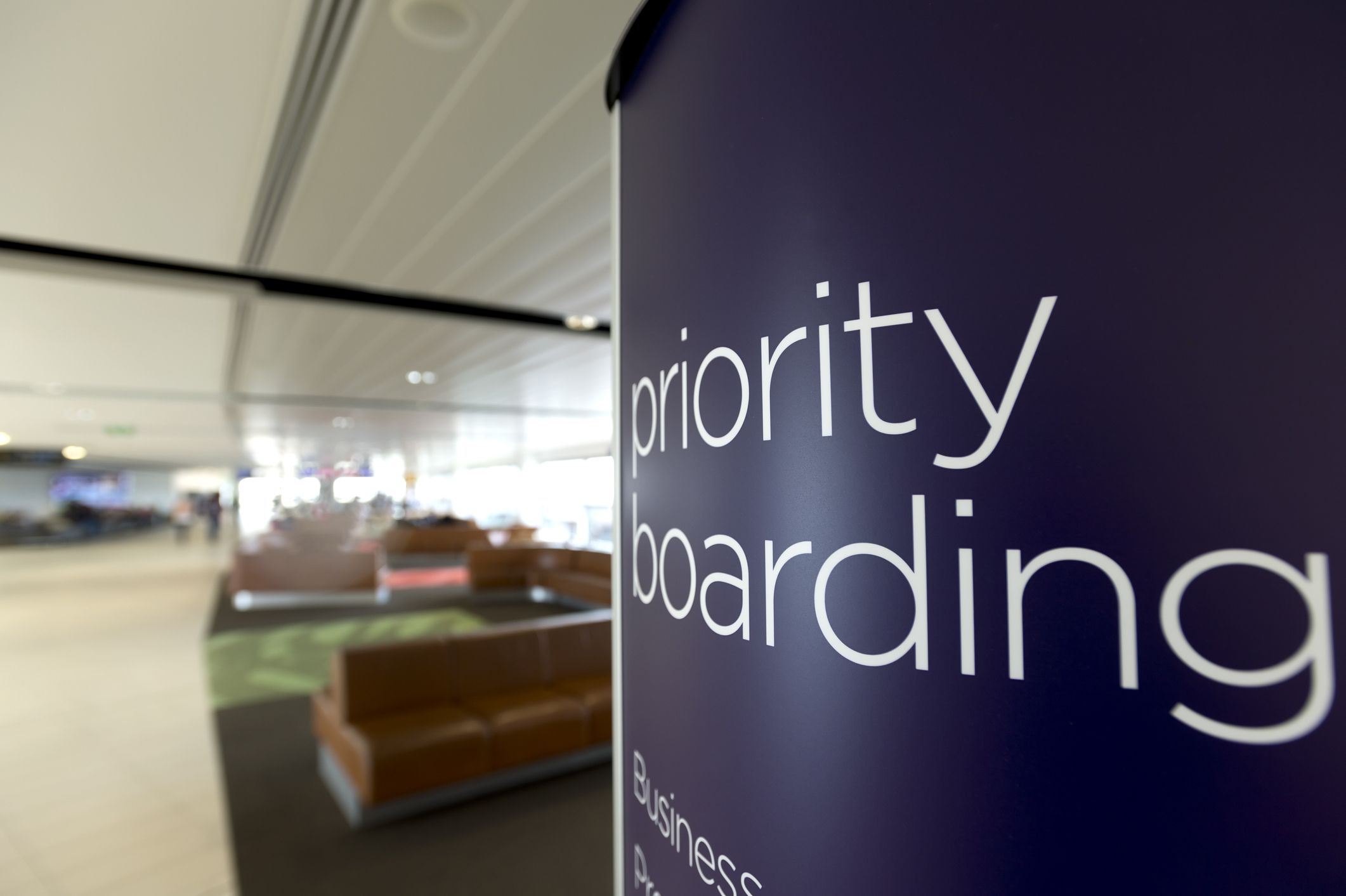 Skilt med teksten Priority Boarding for business- og førsteklassepassagerer ved en gate i en lufthavn