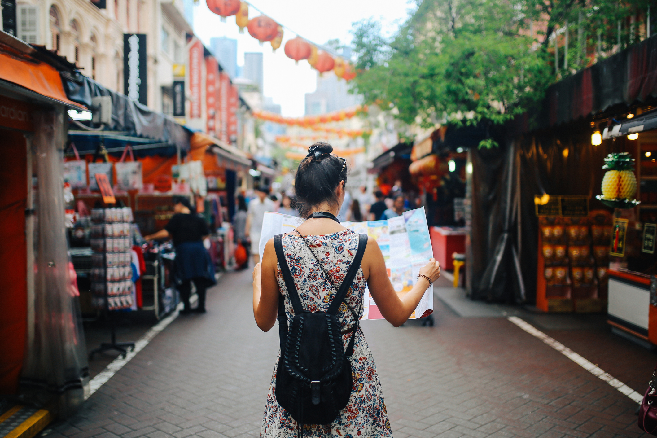 Woman with city map in an alley with open shops