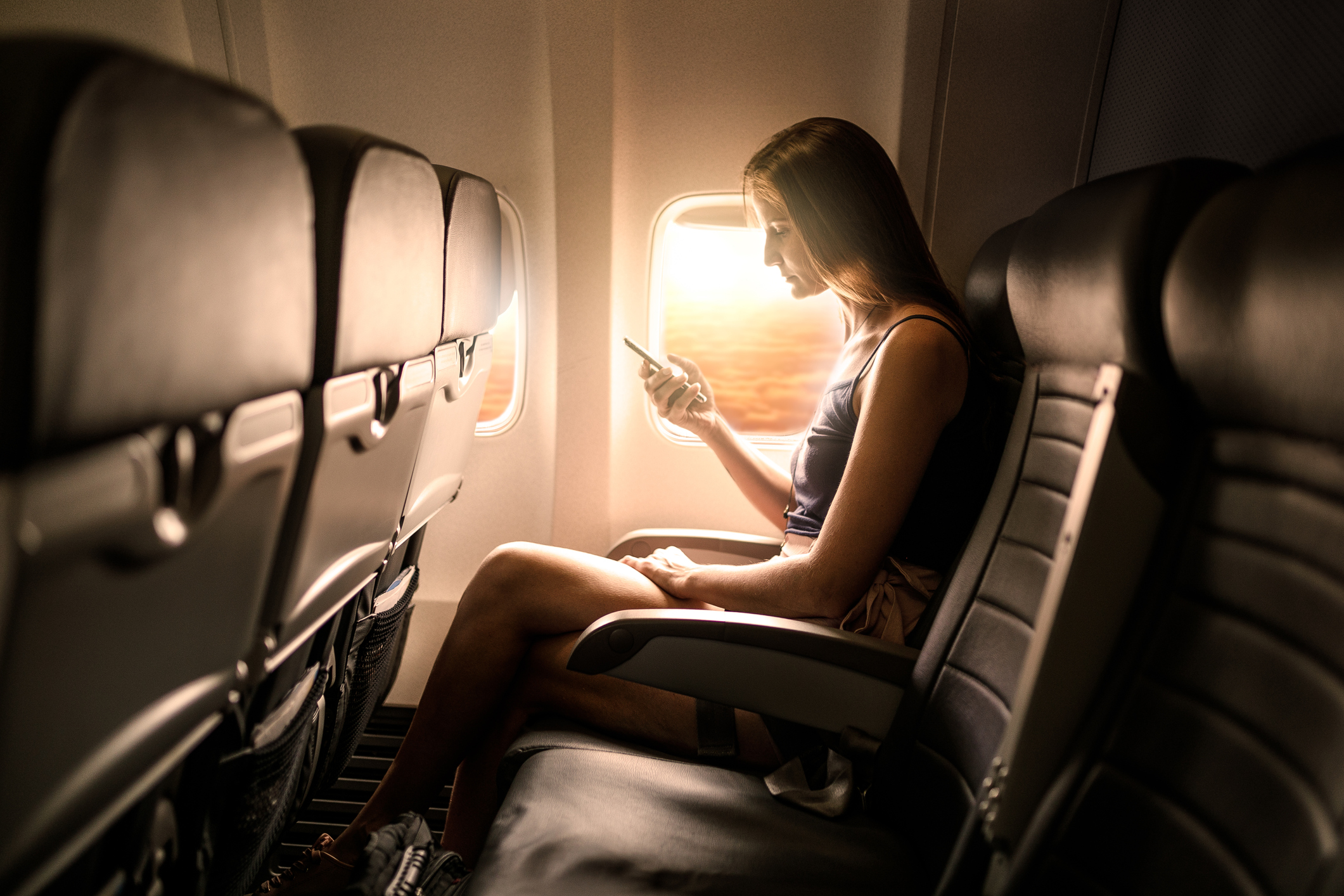 Jonge vrouw op mobiele telefoon op vliegtuig