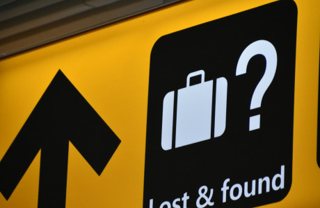 Directional yellow sign at the airport with a white writing "Lost & Found" and a suitcase depicted in white on black background