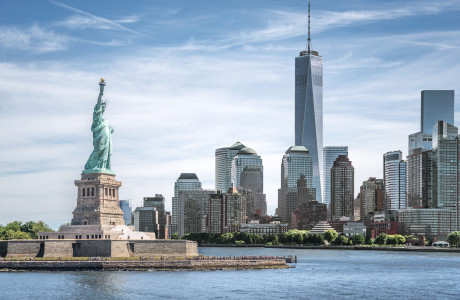 Udsigt over en del af Manhattan, med Frihedsgudinden i forgrunden og One World Trade Center i baggrunden.