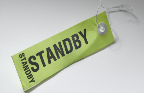Ein Bag Tag mit der Aufschrift „STANDBY“ liegt auf einer weißen Oberfläche.