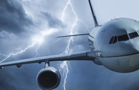Een vliegtuig vliegt door een donderwolk, bliksemflitsen op de achtergrond.