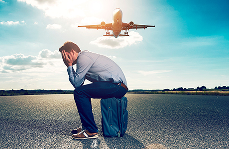 Mann mit Flugangst sitzt auf einem Koffer am Flughafen