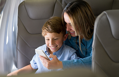 Mutter mit Kind am Smartphone im Flugzeug