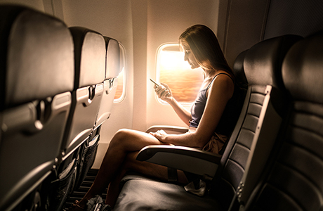 Frau im Flugzeug mit Smartphone
