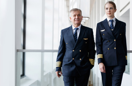 Flight attendant en jonge stewardess in blauw uniform lopen zij aan zij van de terminal naar het vliegtuig om alles klaar te maken voor vertrek.