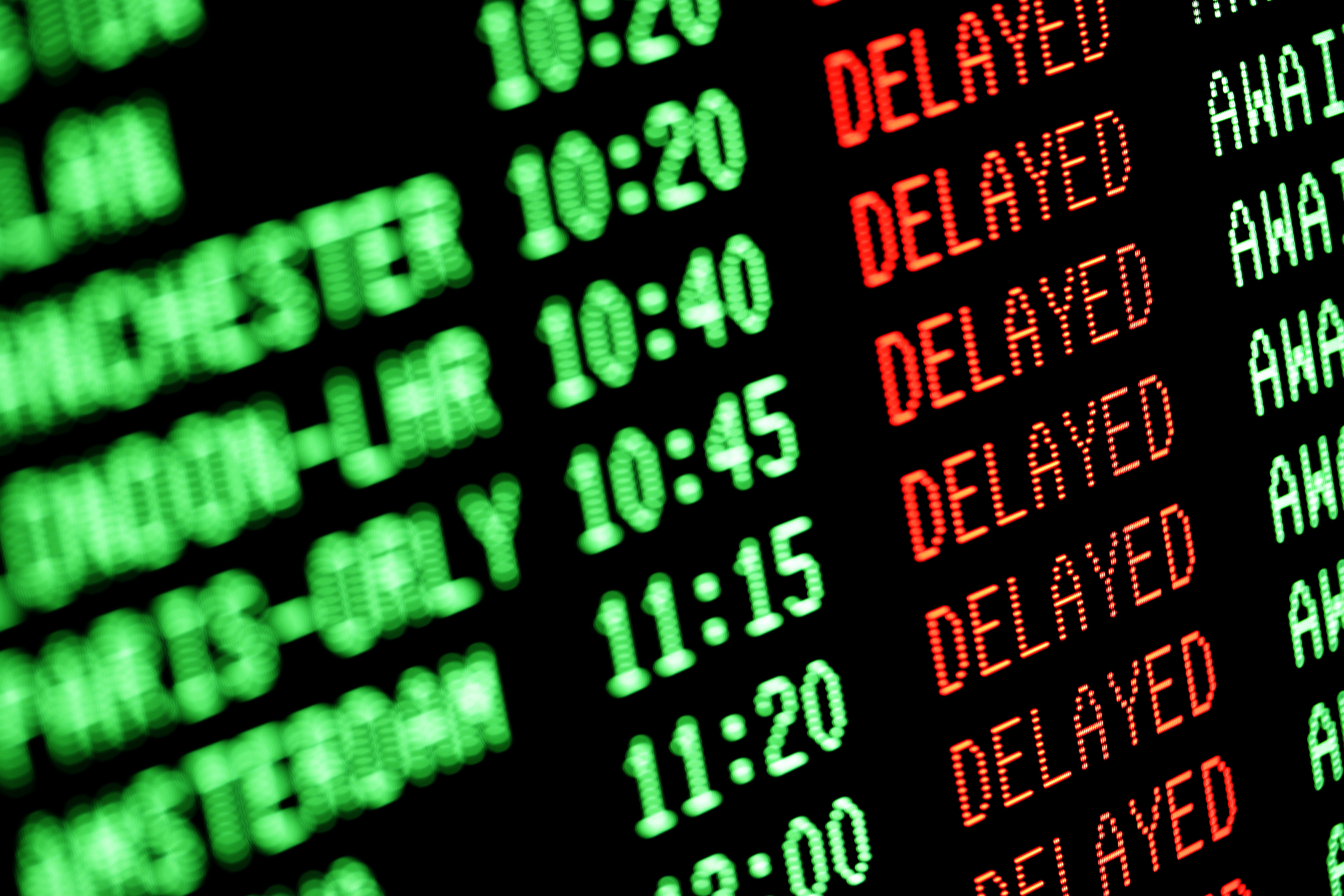 Großaufnahme einer Anzeigetafel vom Flughafen, die die Flugverspätung von mehreren Flügen anzeigt.