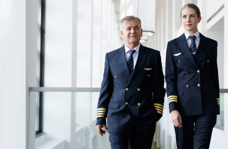 Flugbegleiter und junge Stewardess in blauer Uniform gehen nebeneinander vom Terminal zum Flugzeug, um alles für den Abflug vorzubereiten.